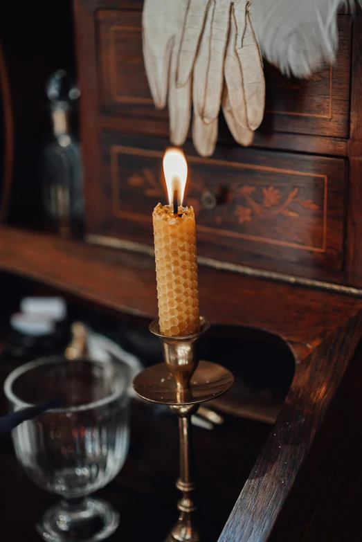 a candle sitting on top of a wooden table, brass beak, honeycomb, victoriana, apothecary