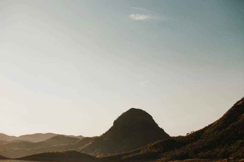 a large body of water with mountains in the background, a picture, unsplash contest winner, australian tonalism, on top of a hill, perfect crisp sunlight, creating a thin monolith, low - angle shot