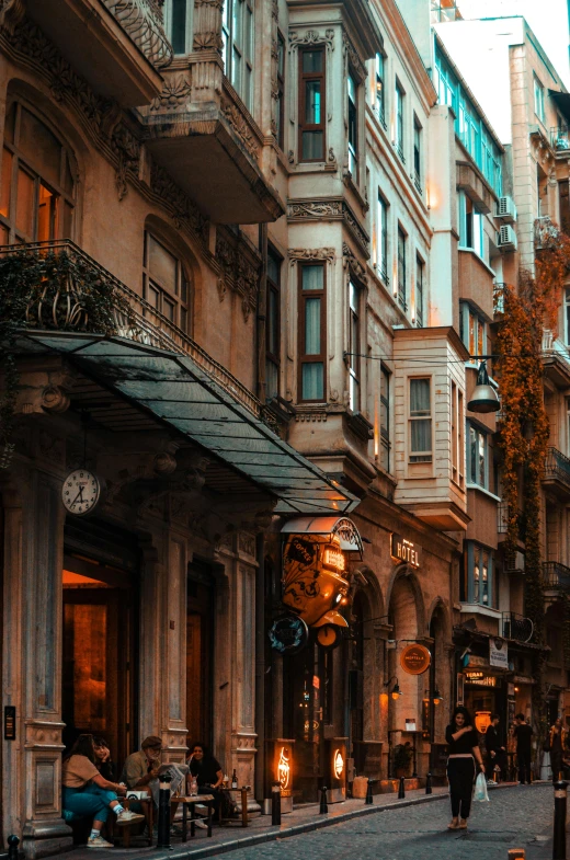 a city street filled with lots of tall buildings, by Niyazi Selimoglu, pexels contest winner, art nouveau, warm street lights store front, brown, neoclassicism style, autumnal