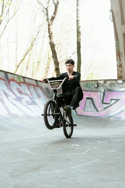 a man riding a bike up the side of a ramp, inspired by Seb McKinnon, at a park, posing for camera, sholim, black