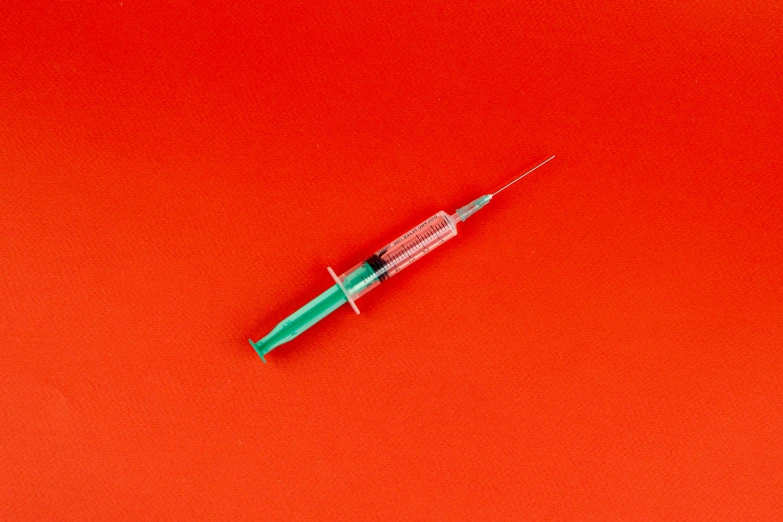 a syll sitting on top of a red surface, syringe, detailed product image, green saliva, taken in the 2000s