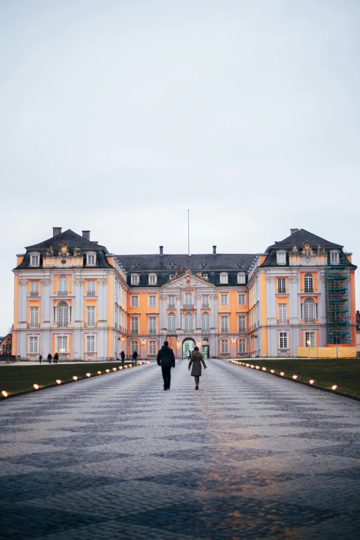 two people walking in front of a large building, pexels contest winner, baroque, dark pastel castle background, detmold, a cozy, lawn