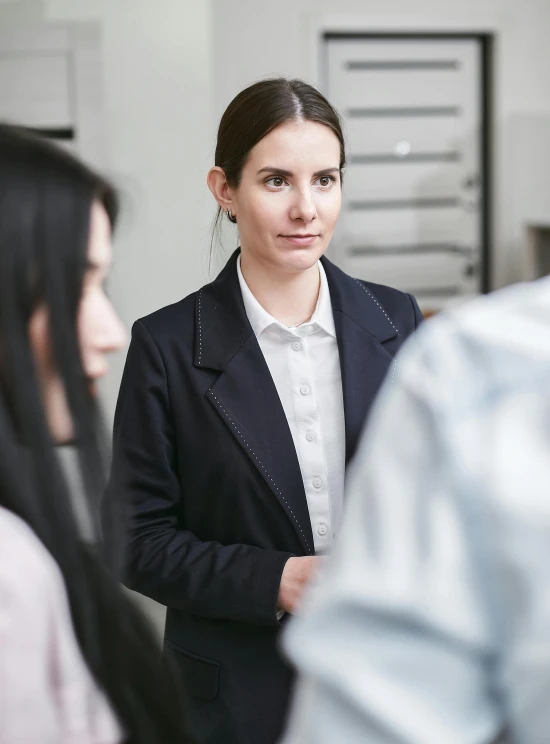 a woman in a business suit talking to a group of people, a picture, arbeitsrat für kunst, looking serious, high-quality photo, in a lab, professional profile photo