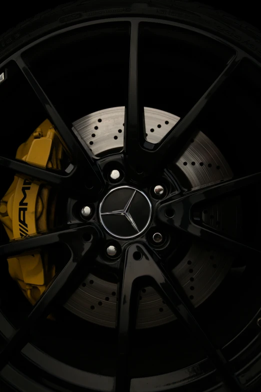 a close up of a wheel on a car, muted brown yellow and blacks, detailed product image, mercedez benz, black on black