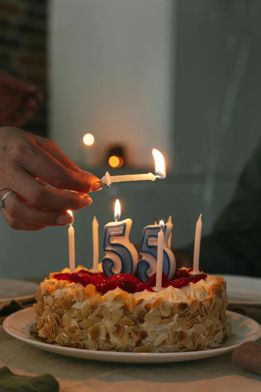 a person lighting candles on a birthday cake, a photo, by Sam Dillemans, pexels, hyperrealism, five score years ago, 50 years old, promo image, with a long