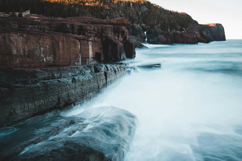 a large body of water next to a rocky shore, unsplash contest winner, water running down the walls, quebec, coastal cliffs, faded glow