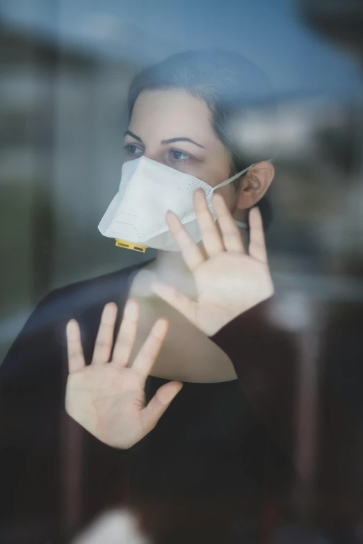 a woman wearing a face mask looking through a window, happening, hand, square, particulate, ad image