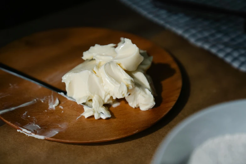 a piece of butter sitting on top of a wooden plate, by Jessie Algie, unsplash, best mayonnaise, with white skin, spoon placed, carefully crafted