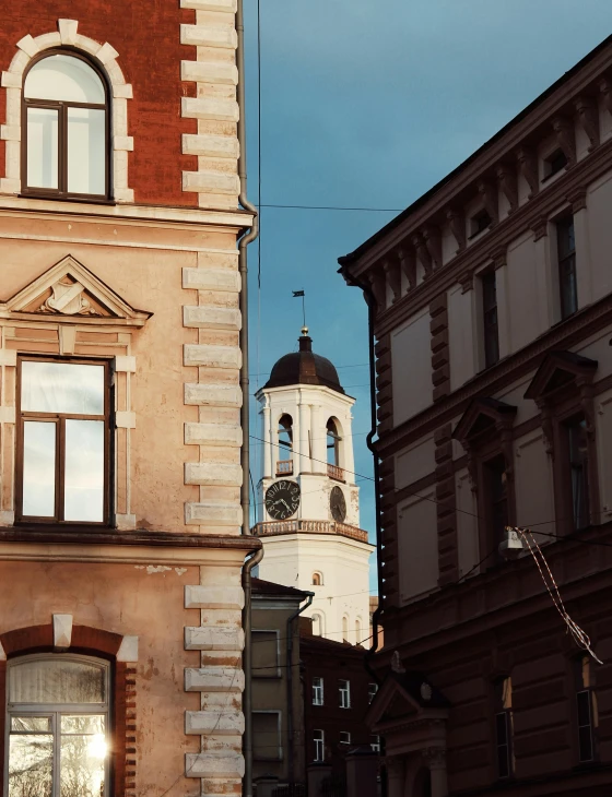 a clock that is on the side of a building, a photo, by Emma Andijewska, pexels contest winner, baroque, neoclassical tower with dome, finland, narrow and winding cozy streets, afternoon light