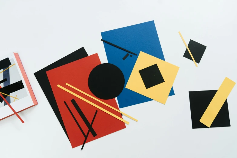 a couple of pieces of art sitting on top of a table, inspired by El Lissitzky, unsplash, suprematism, chopsticks, cardstock, primary colors, black