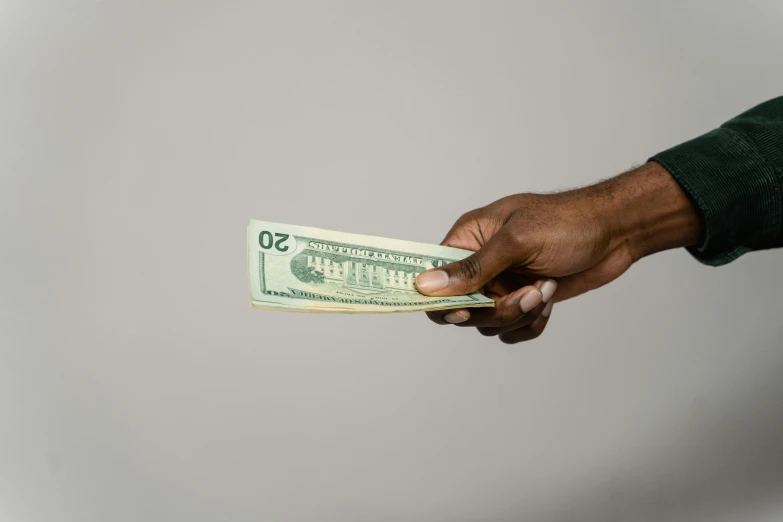 a man holding a stack of money in his hand, by Matija Jama, pexels contest winner, hurufiyya, on a pale background, man is with black skin, flat, usa