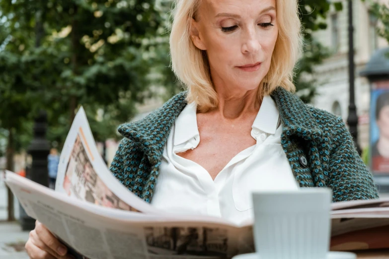 a woman sitting at a table reading a newspaper, trending on unsplash, private press, close up of a blonde woman, middle - age, 15081959 21121991 01012000 4k, al fresco