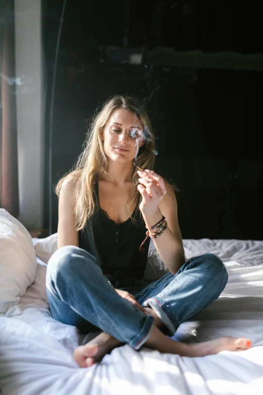 a woman sitting on a bed smoking a cigarette, a portrait, trending on unsplash, marijuana smoke, denim, hotel room, britt marling style