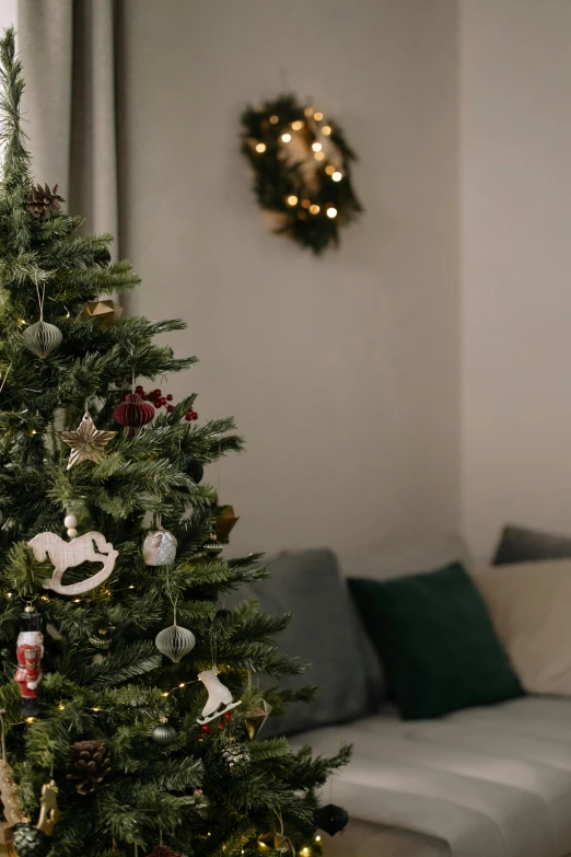 a christmas tree in a living room next to a couch, pexels, dynamic closeup, multiple stories, grey, a green