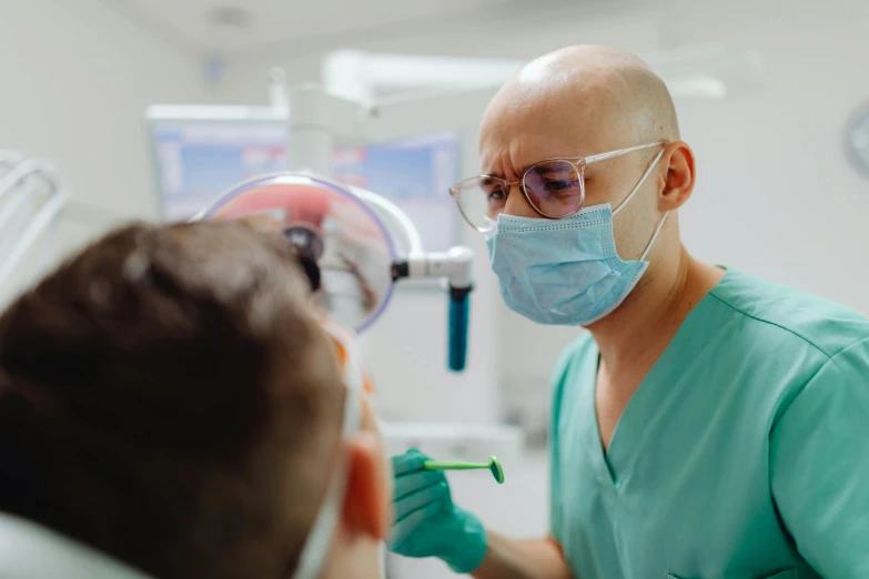 a man getting his teeth examined by a dentist, by Adam Marczyński, pexels contest winner, hurufiyya, wearing mask, profile image, thumbnail, distant photo