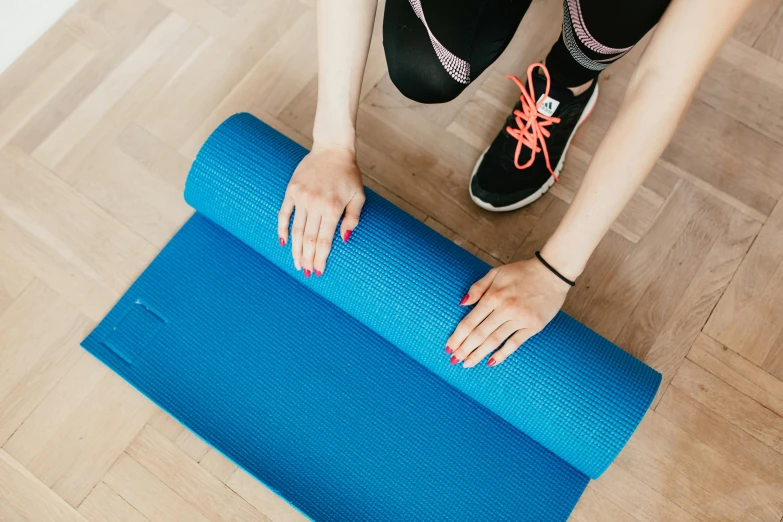 a woman rolling up a yoga mat on the floor, by Rachel Reckitt, trending on pexels, private press, background image, blue print, advertising photo