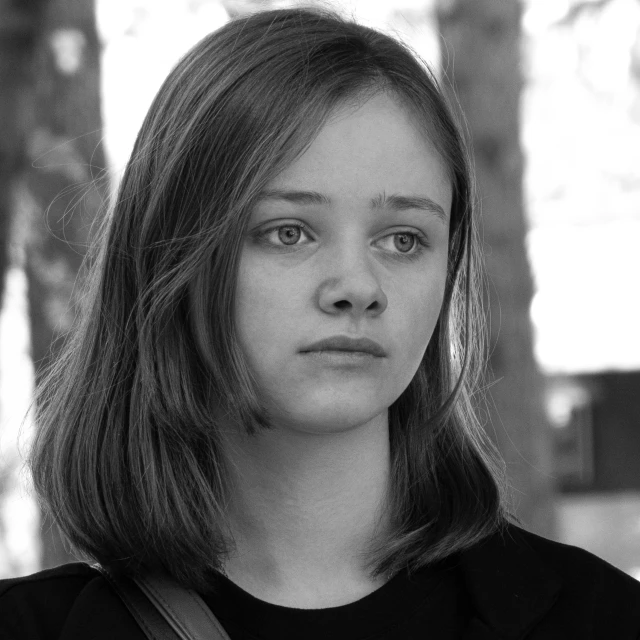 a black and white photo of a woman holding a cell phone, by Louisa Matthíasdóttir, sadie sink, movie still 8 k, headshot profile picture, square