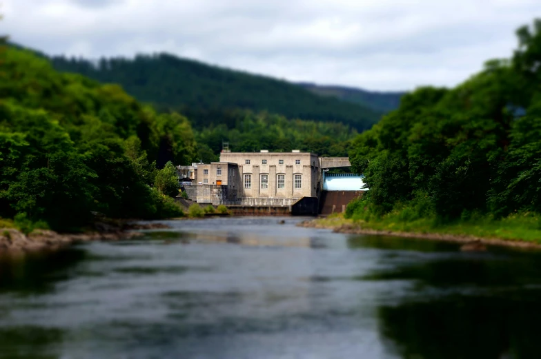 a river running through a lush green forest filled with trees, a tilt shift photo, by John Murdoch, pexels contest winner, photorealism, building along a river, scotland, replica model, water reservoir