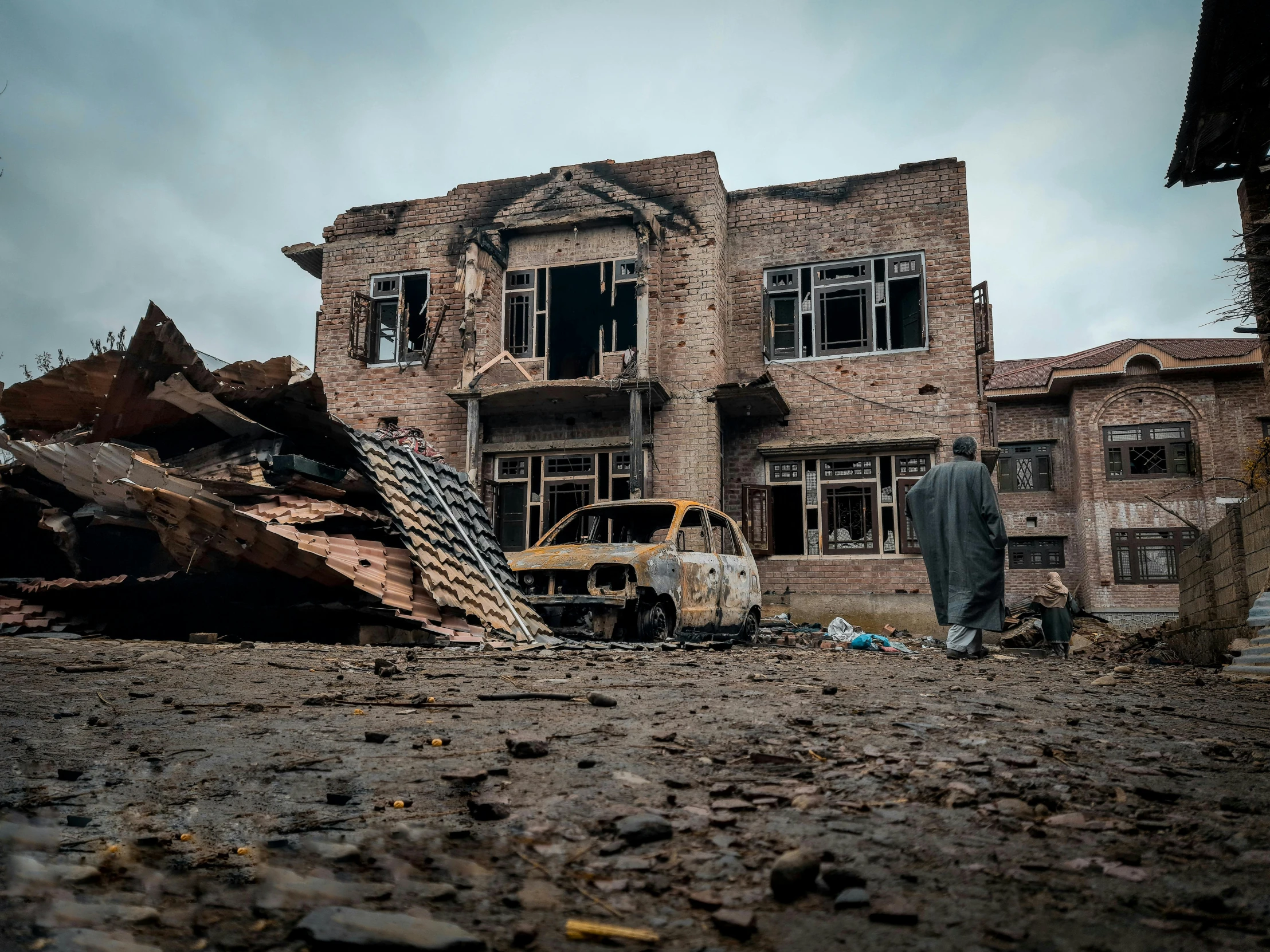 a man standing in front of a destroyed building, by Benjamin Block, pexels contest winner, taliban, view from the streets, thumbnail, vehicle