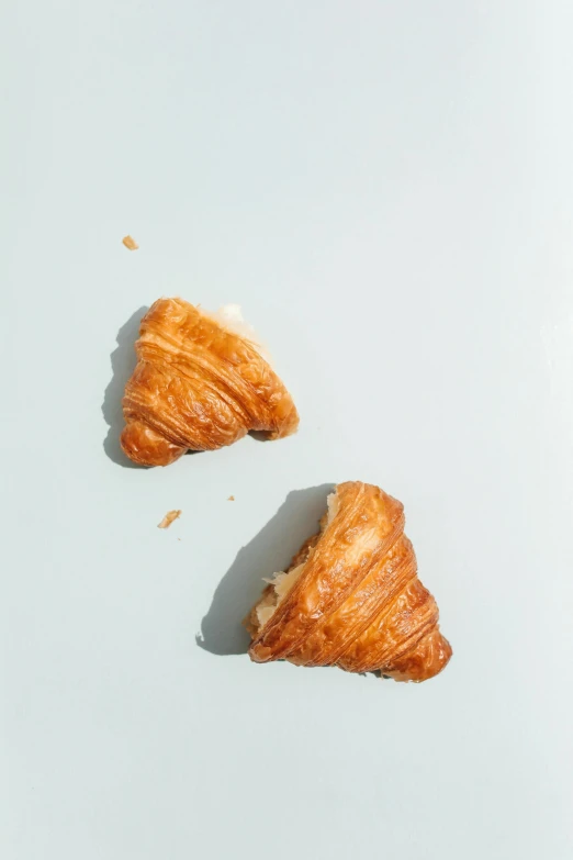 a couple of croissants sitting on top of a table, on a pale background, shot with sony alpha, summertime, hasselblatt