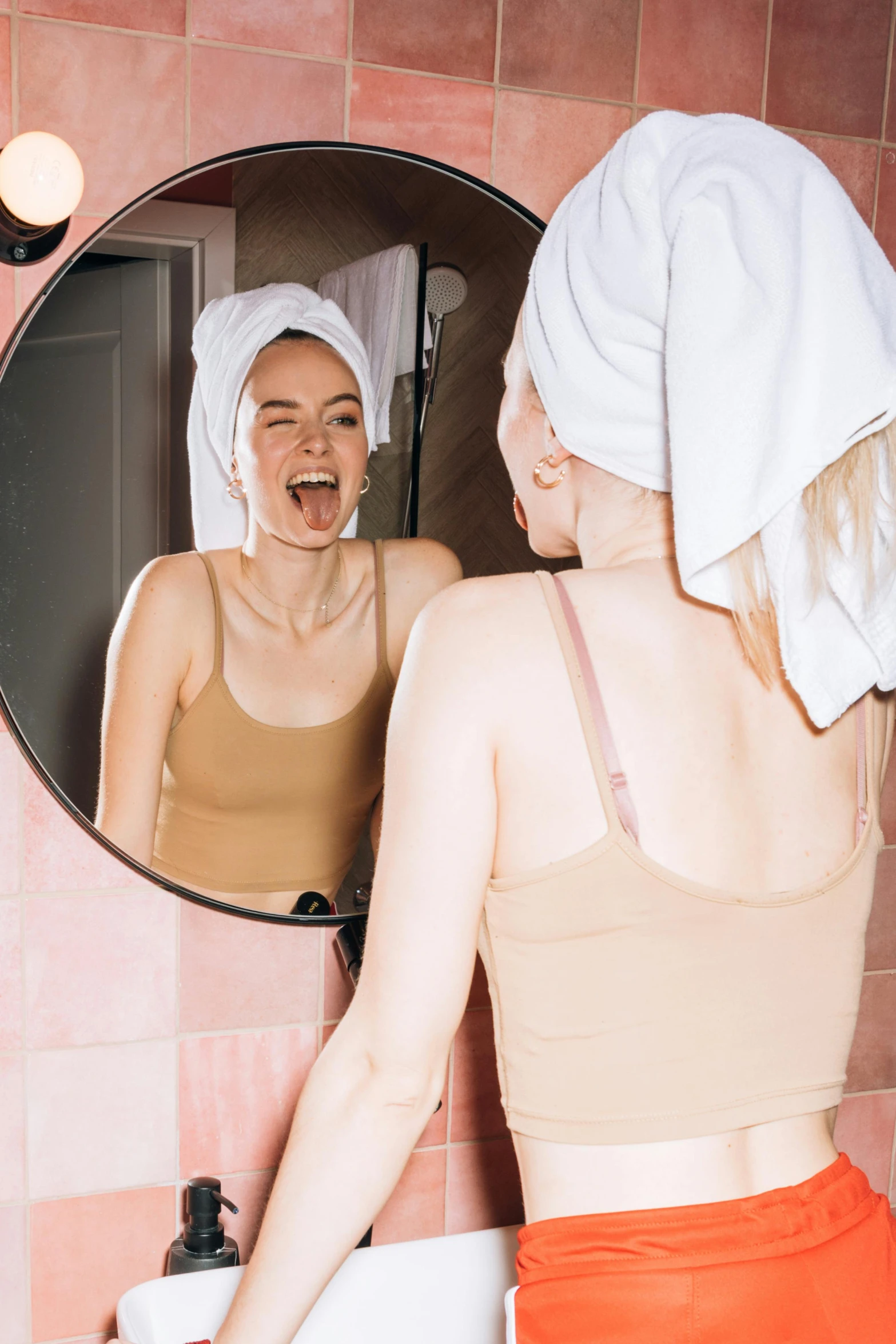 a woman standing in front of a bathroom mirror, by Julia Pishtar, trending on pexels, happening, head bent back in laughter, pastel pink skin tone, silicone skin, panoramic view of girl
