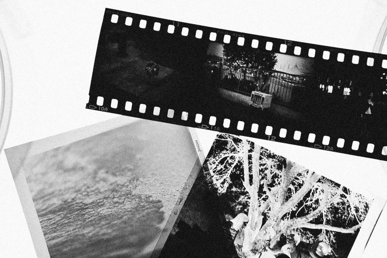 a couple of black and white pictures sitting on top of a table, a black and white photo, unsplash, serial art, shot of film, grainy tape, art house film aesthetic, vintage sci - fi soft grainy