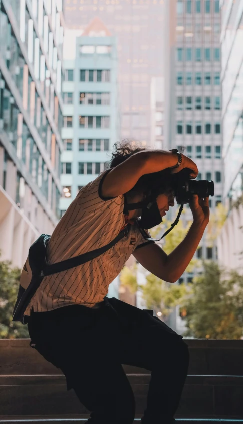 a man riding a skateboard down a street next to tall buildings, by Carey Morris, pexels contest winner, holding a big camera, mana shooting from his hands, headshot, holding a dslr camera