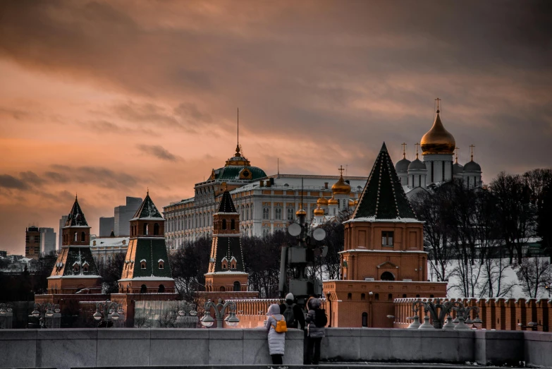a couple of people standing on top of a bridge, inspired by Vasily Surikov, pexels contest winner, moscow kremlin, gray and orange colours, early evening, gold and red