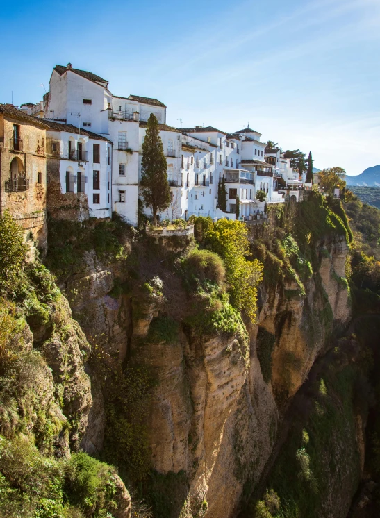 a small town perched on the edge of a cliff, flowing white robes, spanish princess, square, no crop