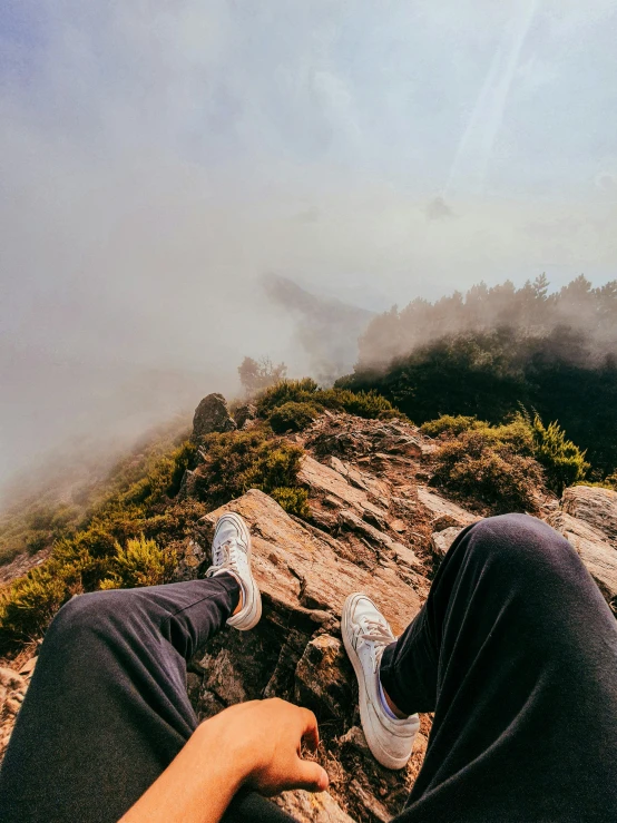 a person sitting on top of a mountain, legs taking your pov, profile image