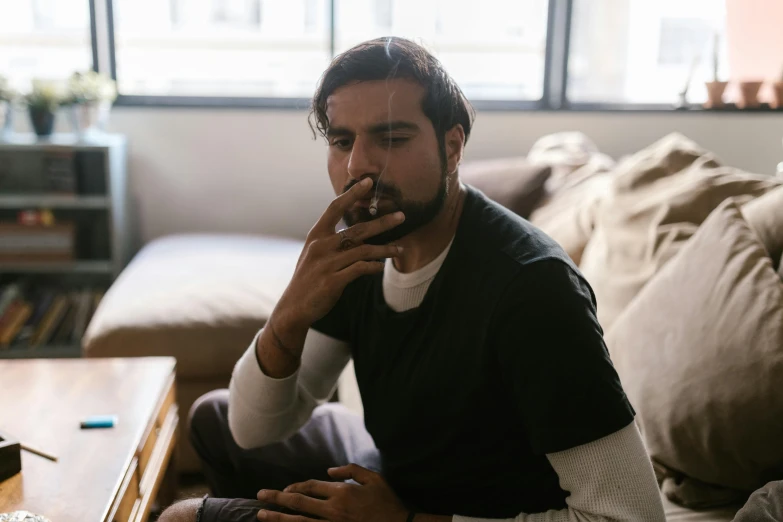 a man sitting on a couch smoking a cigarette, a portrait, inspired by Elsa Bleda, pexels contest winner, renaissance, aboriginal australian hipster, profile image, vinny from vinesauce, ganja