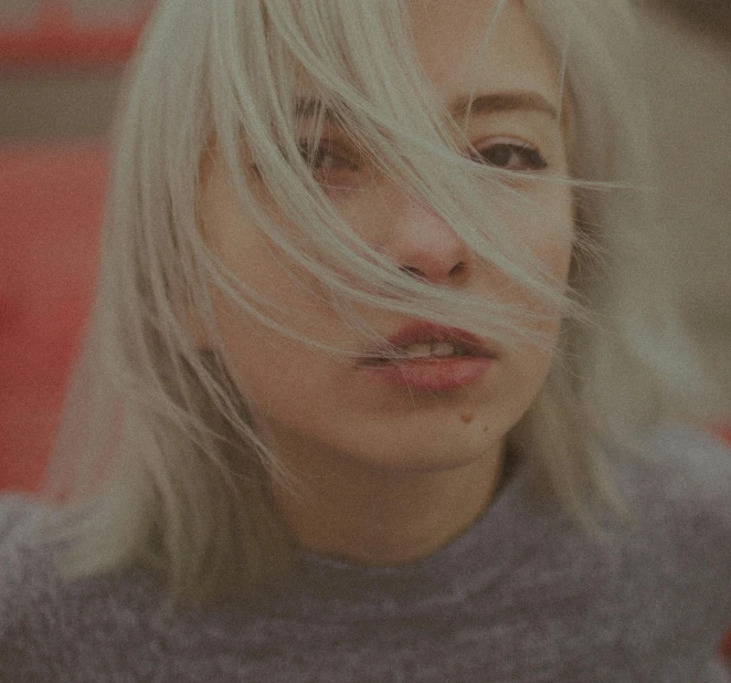 a woman with blonde hair blowing in the wind, an album cover, inspired by Elsa Bleda, trending on unsplash, realism, white bangs, 🤤 girl portrait, low quality grainy, color photograph portrait 4k