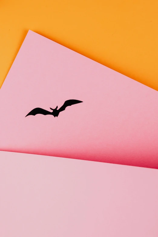 a pink envelope with a black bird on it, trending on pexels, conceptual art, vampire bats, material design, batman, multicoloured