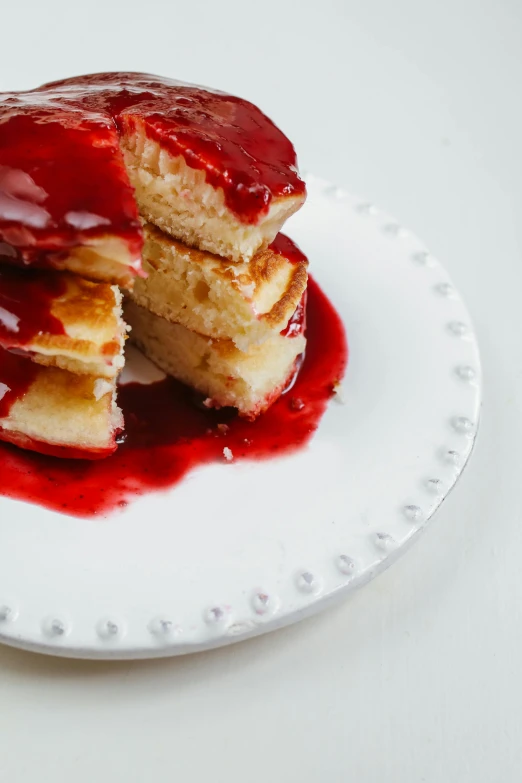 a stack of pancakes sitting on top of a white plate, a portrait, unsplash, red liquid, cuts, glazed, eating cakes