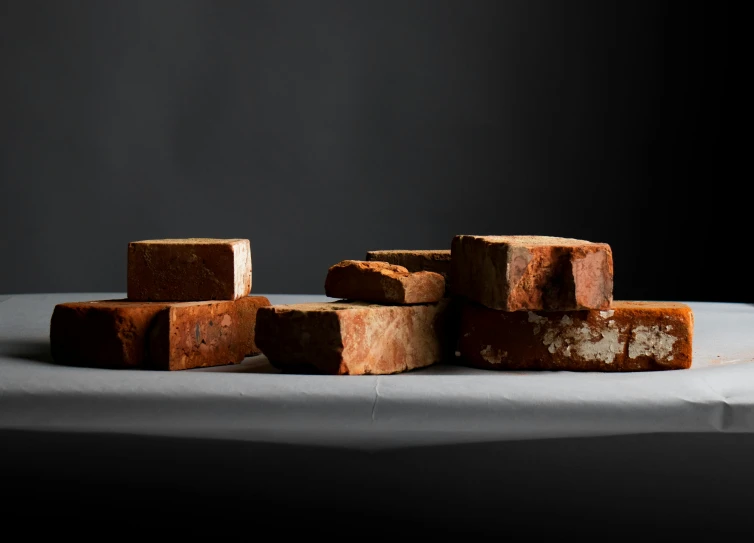 a pile of bricks sitting on top of a table, by Helen Stevenson, process art, (rust), medium format, bread, ignant