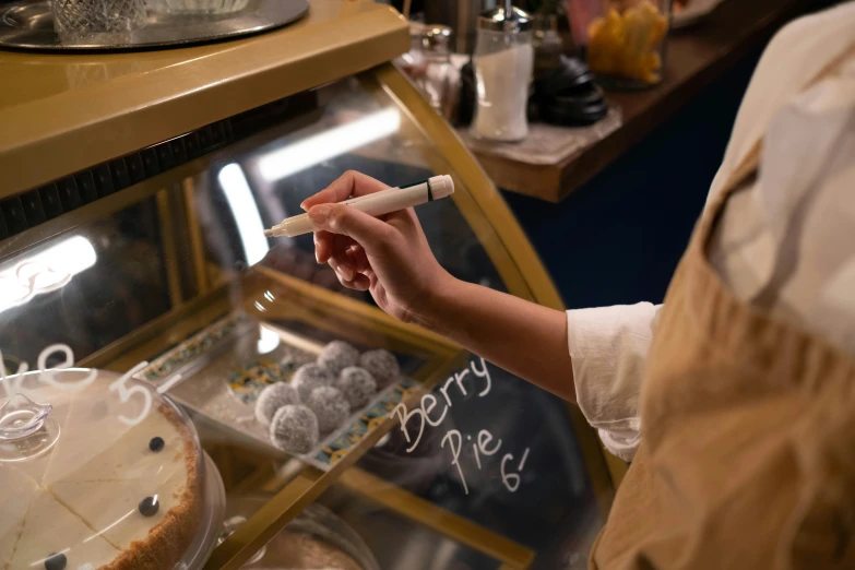 a woman that is standing in front of a cake, permanent marker, at the counter, medium close - up ( mcu ), bixbite