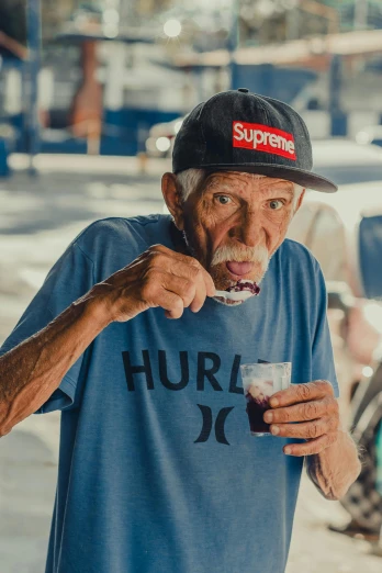 a man standing on the side of a street eating food, a portrait, by William Berra, pexels contest winner, harriet tubman skateboarding, an 80 year old man, portrait of danny gonzalez, hydration