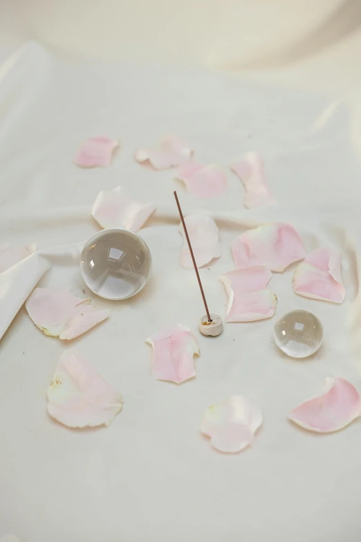 a clock sitting on top of a white table, an album cover, inspired by Hsiao-Ron Cheng, glass orbs, rose petals, close up. macro. hyper realistic, incense