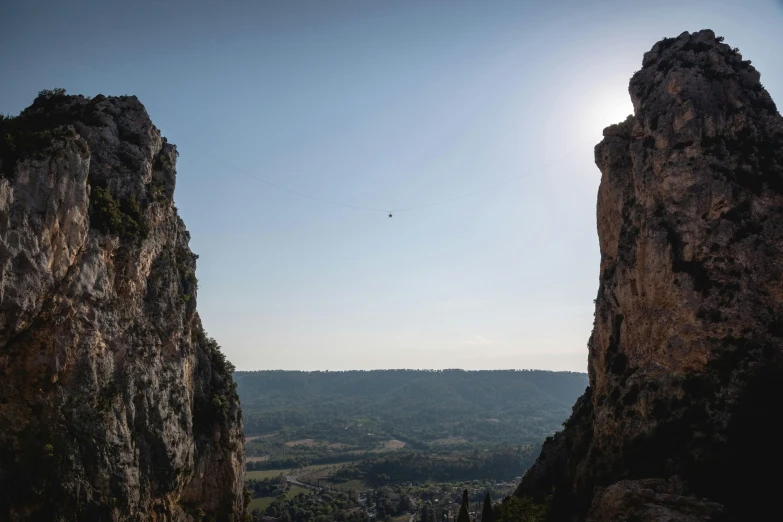 a couple of large rocks sitting next to each other, a picture, by Raphaël Collin, pexels contest winner, les nabis, flying over the horizon, as seen from the canopy, hanging rope, southern european scenery