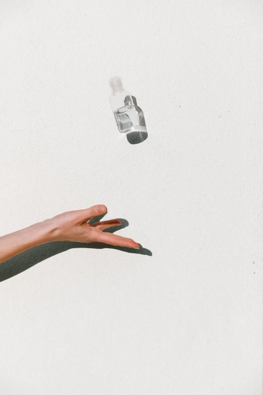 a hand reaching for a bottle of water, an album cover, by Pablo Rey, trending on pexels, postminimalism, female floating, throwing cards in the air, grainy film photo, transparent