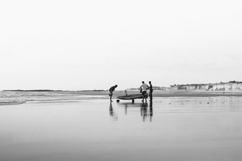 a group of people standing on top of a beach next to the ocean, a black and white photo, by Caro Niederer, unsplash, minimalism, rowing boat, mechanics, playing at the beach, craigville