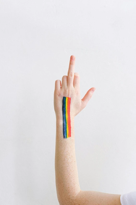 a person with a rainbow painted on their arm, an album cover, by Nicolette Macnamara, trending on pexels, synchromism, giving the middle finger, striped, 15081959 21121991 01012000 4k, stick and poke