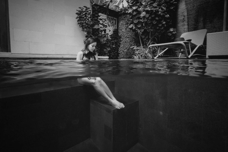 a black and white photo of a woman sitting in a pool, by Emma Andijewska, unsplash contest winner, surrealism, tithi luadthong, 8k 50mm iso 10, terrified, beautiful surroundings