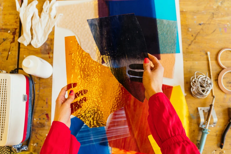 a woman is working on a piece of art, a screenprint, inspired by Howard Hodgkin, trending on unsplash, shiny plastic, cut up collage, standing in gold foil, cast glass