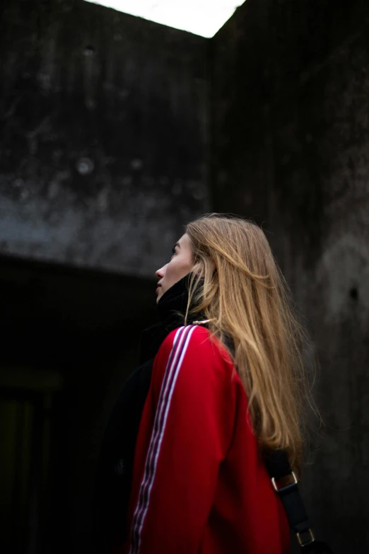 a woman with long hair wearing a red jacket, inspired by Elsa Bleda, pexels contest winner, looking around a corner, young woman looking up, wearing adidas clothing, face profile