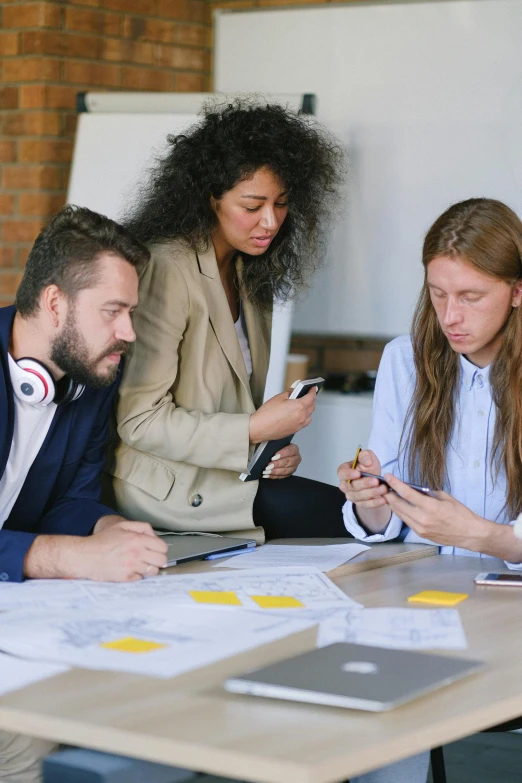 a group of people sitting around a table looking at cell phones, trending on pexels, arbeitsrat für kunst, architect studio, wearing business casual dress, 9 9 designs, concentrated