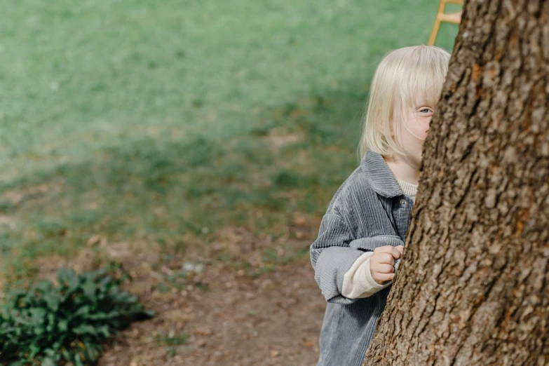 a little girl standing next to a tree, inspired by Elsa Beskow, pexels contest winner, hiding behind obstacles, grey, playing, 15081959 21121991 01012000 4k