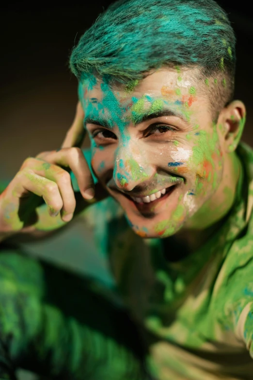 a man with green paint on his face talking on a cell phone, inspired by John Luke, trending on pexels, happy color, colorful]”, attractive man, posing for a picture