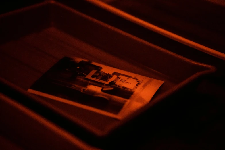 a black and white photo in a box, a hologram, by Daniel Lieske, pexels contest winner, holography, red and orange glow, photocopied, brown atmospheric lighting, high angle close up shot