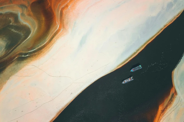 a couple of boats floating on top of a body of water, unsplash contest winner, space art, desert colors, made of oil and water, abstract detail, /r/earthporn